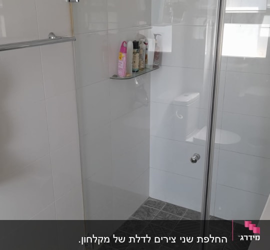 מקלחון זכוכית עם מדף בקבוקים על קיר לבן
